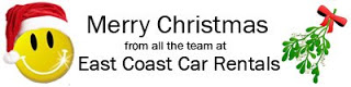 Merry Christmas From All the Team at East Coast Car Rentals with a Smiley Face and Santa Hat
