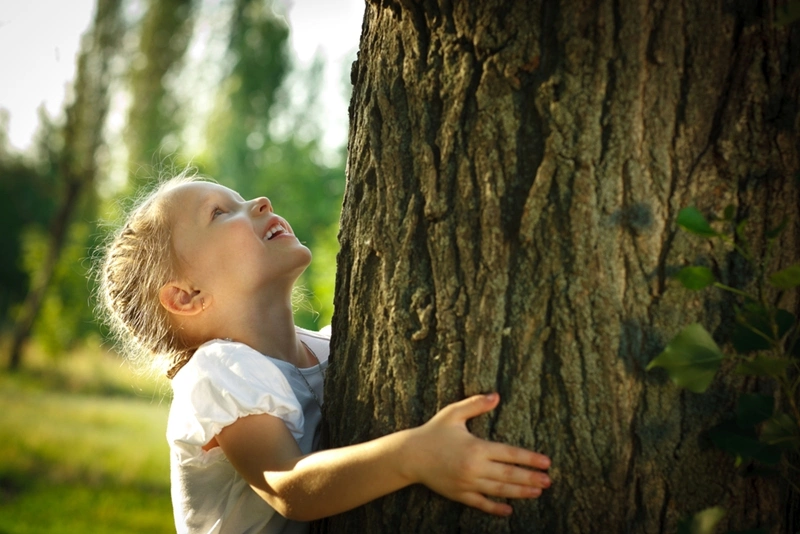 a young girl hugging a large tree