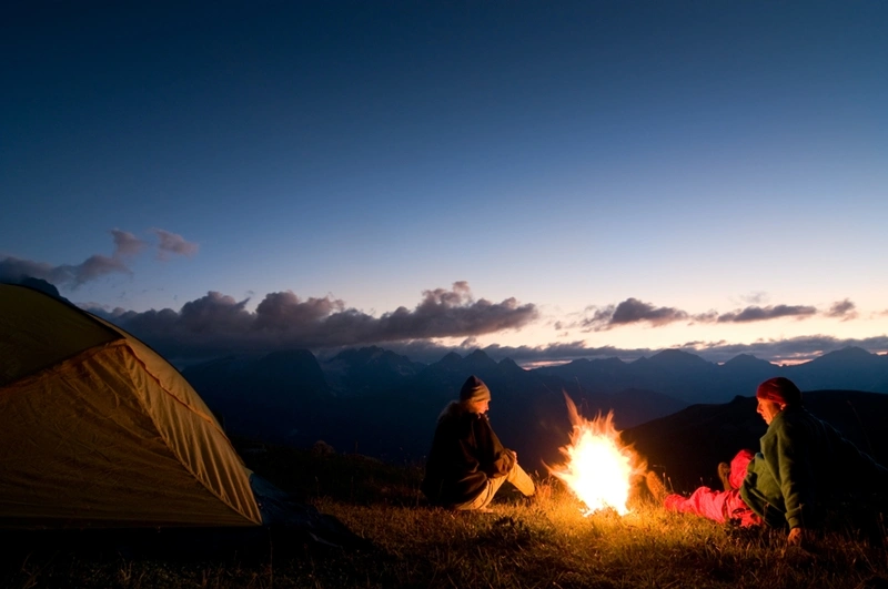 camping at sunset around a fire with the tent set up