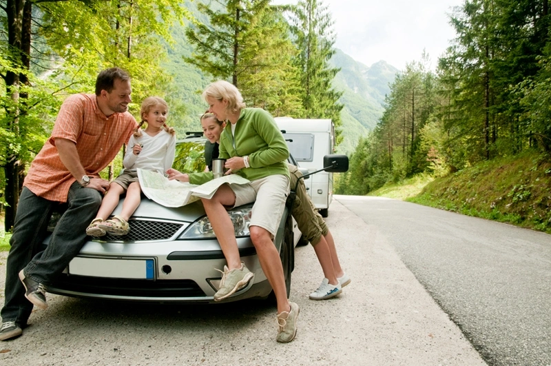 a family checking a map on their car bonnet during camping trip