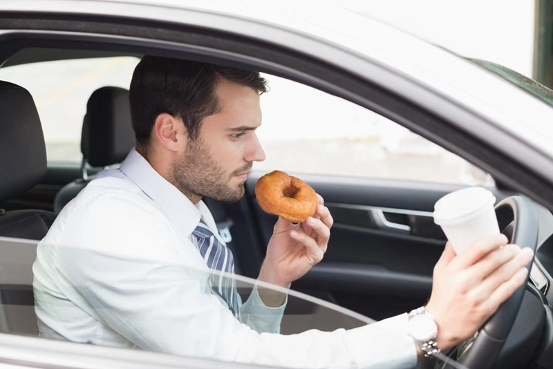 man with a coffee and a donut in a car