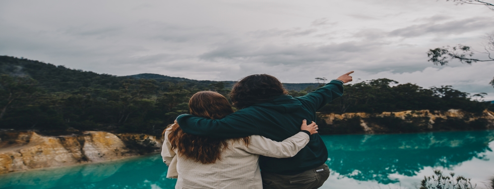 Two people looking over teal blue lake in Tasmania