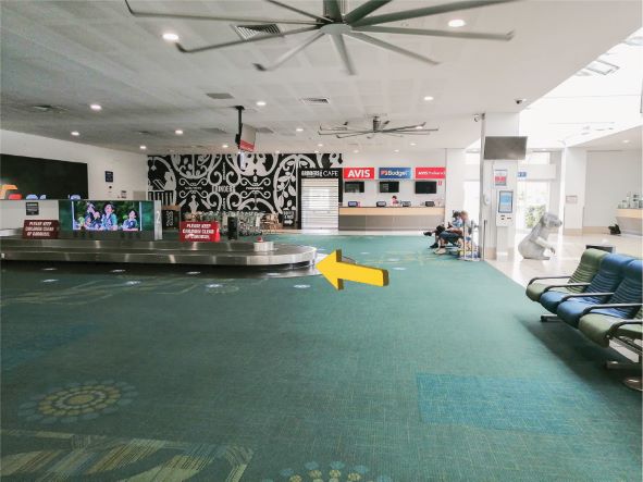 An empty Sunshine Coast Airport Terminal baggage claim area with a yellow arrow pointing towards the baggage claim.