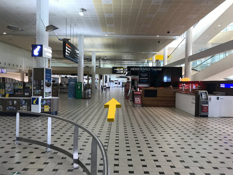 International airport hall with information stands on the left and news on the right.