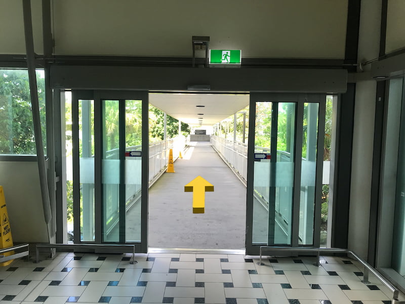 Glass doors exiting the airport to a long sheltered outdoor hallway.