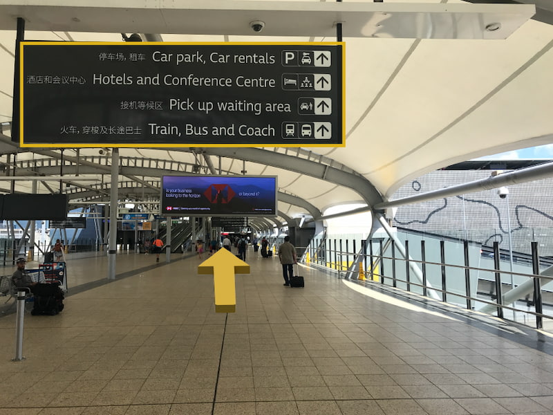 Airport directory sign with yellow arrows directing to continue straight.
