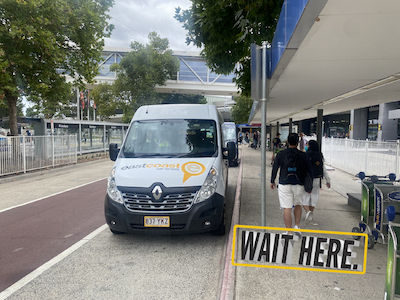 White East Coast Car Rentals Shuttle bus parked, picking up passengers.