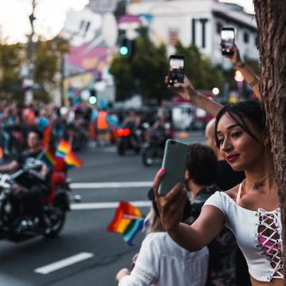 person taking selfie with parade in the background