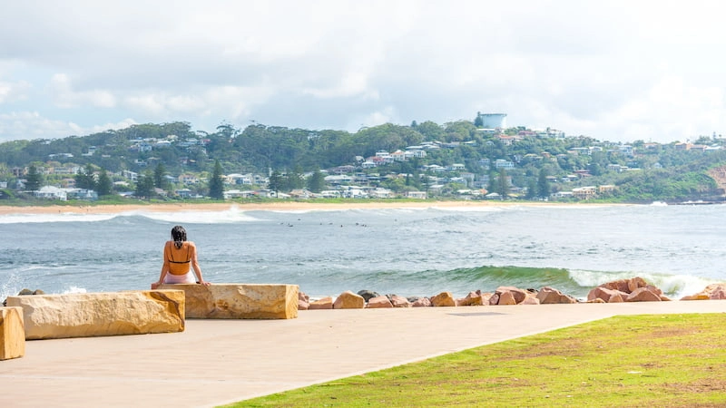 woman sitting at a beach pathway