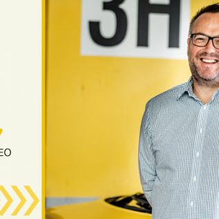 Man smiling with yellow rental car in the background.