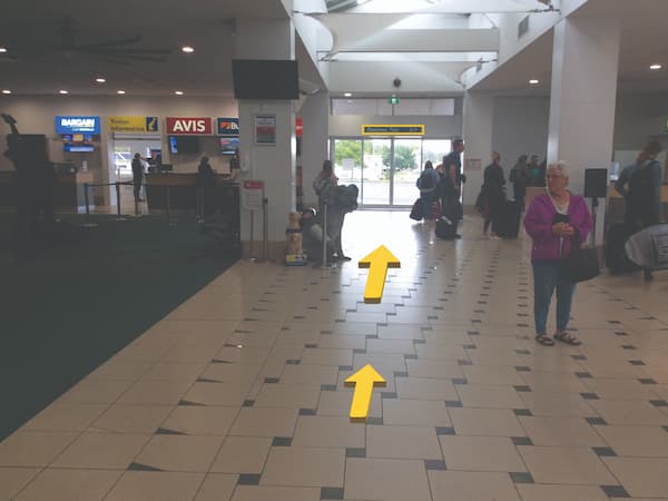 Interior of an airport - yellow arrow pointing straight towards the exit,