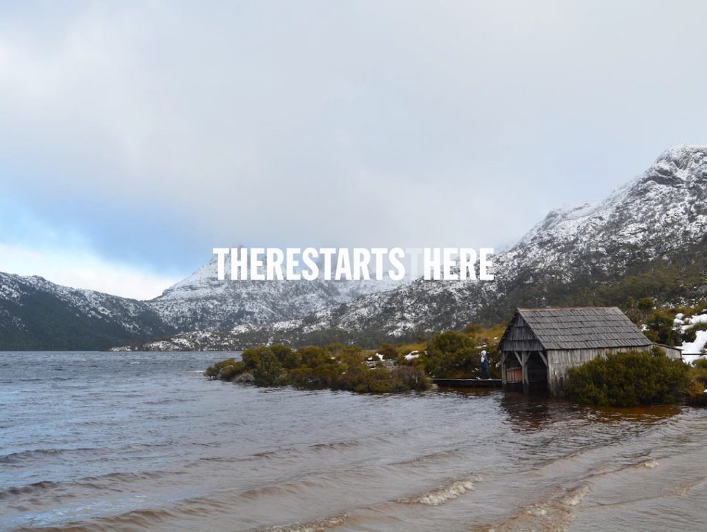 A cabin on the lake surrounded by Mountain Tops with Snow