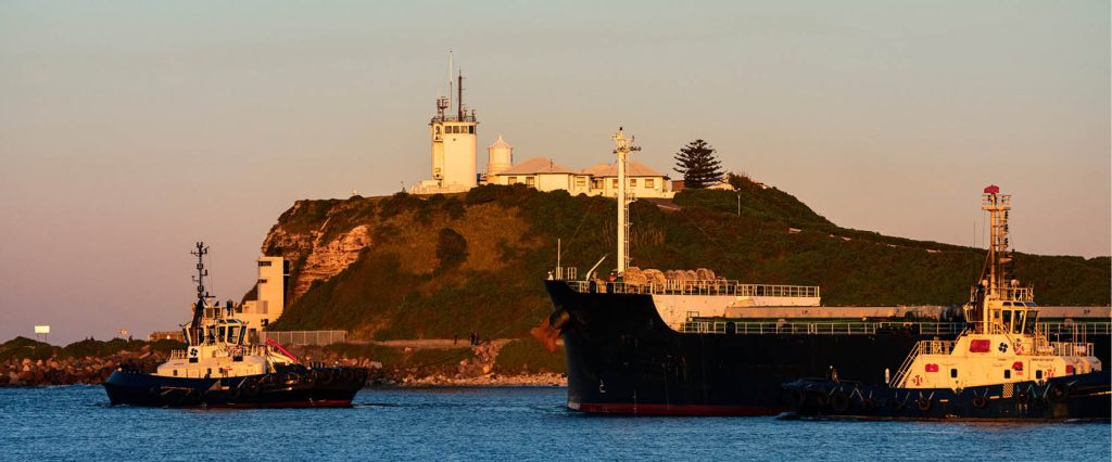 Lighthouse and two ships sailing on the ocean | Featured image for 5 Fun Day Trips Around Newcastle.