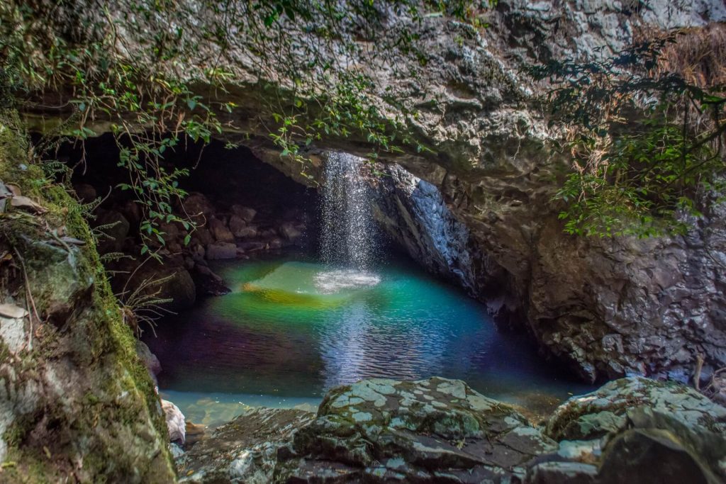 Photo of a waterfall flowing into a pool | Featured image for Outback Queensland Road Trips blog for East Coast Car Rentals.