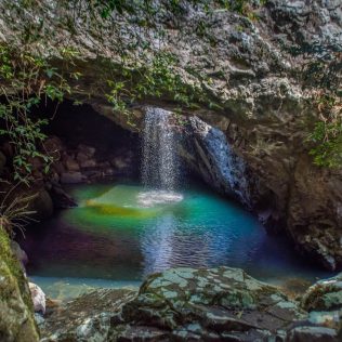 Photo of a waterfall flowing into a pool | Featured image for Outback Queensland Road Trips blog for East Coast Car Rentals.