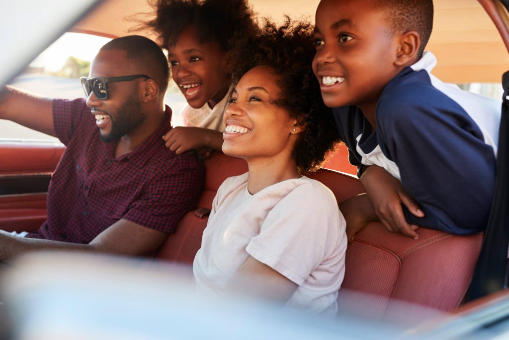 Family of four enjoying driving on a big family road trip | Featured image for Planning a Big Family Road Trip blog for East Coast Car Rentals.