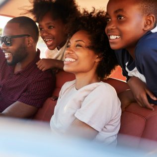 Family of four enjoying driving on a big family road trip | Featured image for Planning a Big Family Road Trip blog for East Coast Car Rentals.